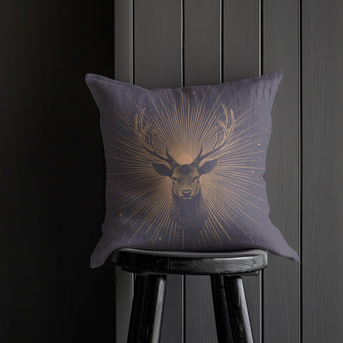 A pillow cover showing a noble stag rendered in shimmering beige against navy blue fabric. Fine beige tan rays extend from the deer's head like sunbeams, with scattered stars.